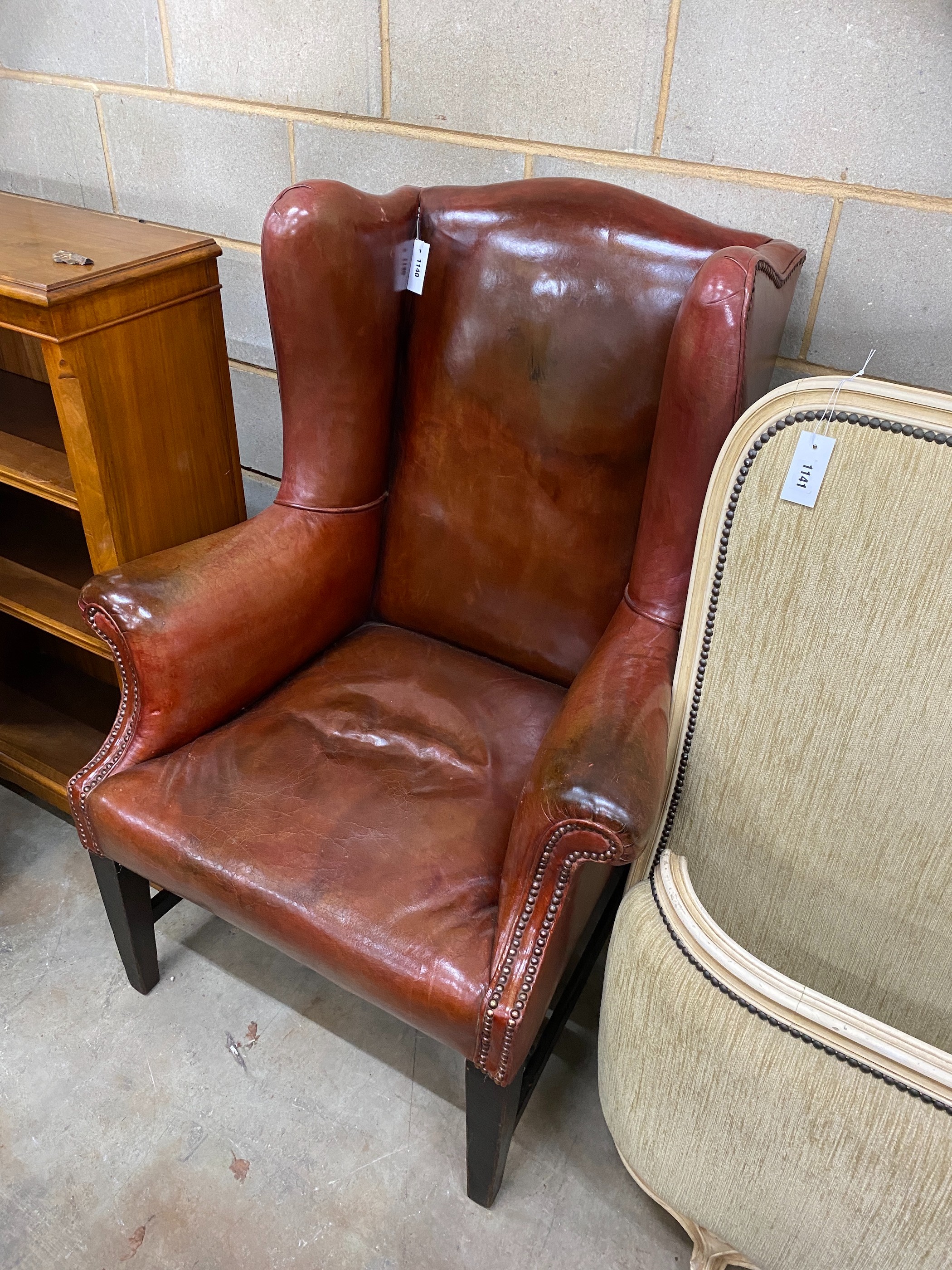 An antique burgundy leather wing armchair, width 82cm, depth 84cm, height 112cm